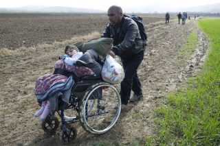 La foto del migrante che spinge un bambino su una sedie a rotelle